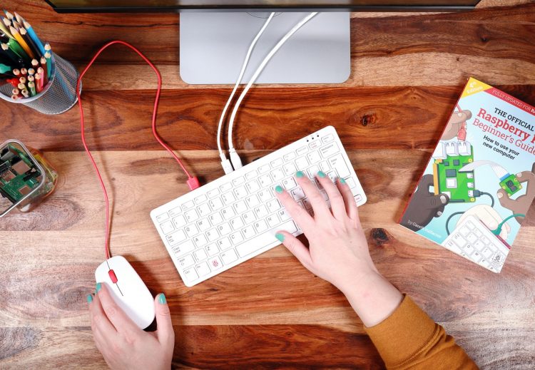 a photo of the raspberry pi 400 with someone's hand on the keyboard