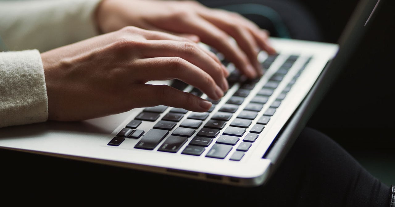 hands typing on a laptop keyboard